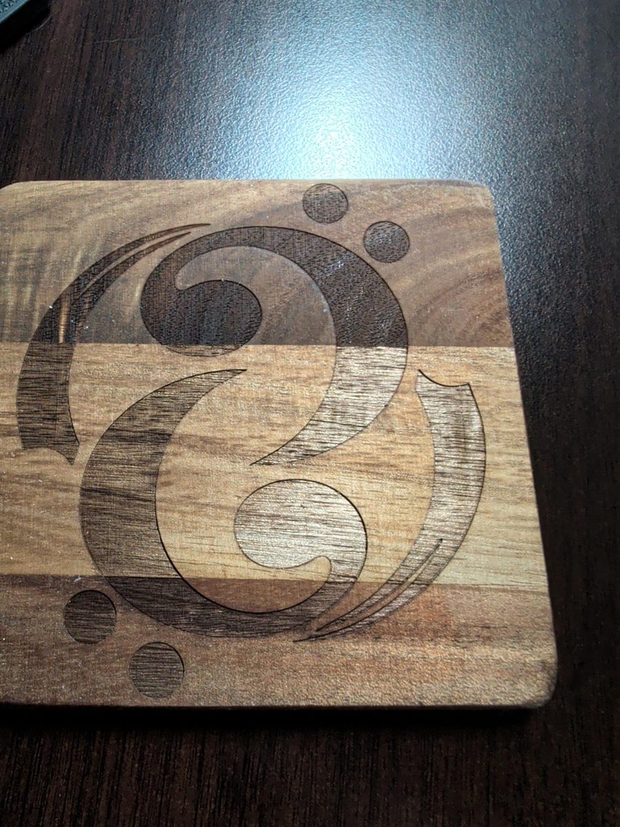 Bass clef logo laser engraved into a wood coaster